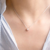 close-up view of a Silver necklace with a star pendant on a person wearing a white shirt.